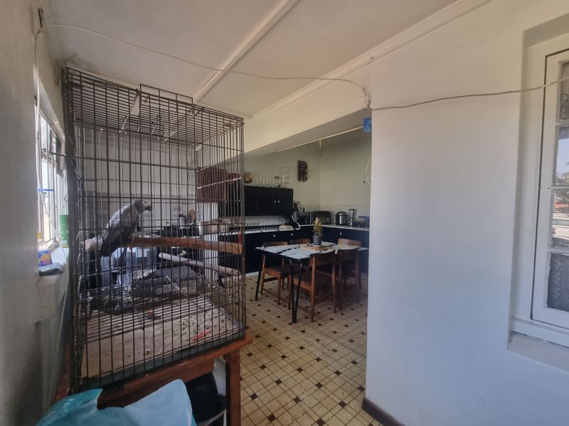A functional kitchen area featuring fitted cabinetry and tiled flooring, currently showing signs of wear and requiring cosmetic updates.