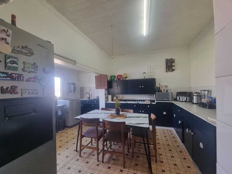 A functional kitchen featuring dark cabinetry, laminate countertops, and tiled flooring, offering potential for modernization and aesthetic updates.
