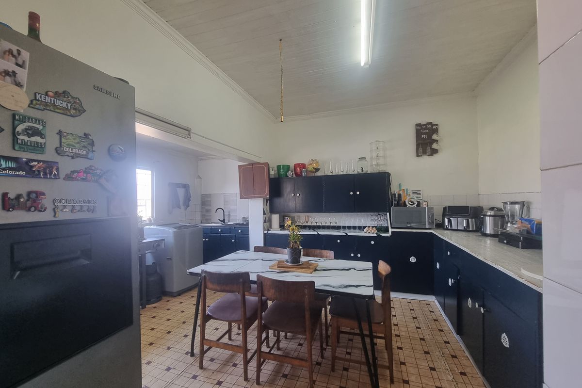 A functional kitchen featuring dark cabinetry, laminate countertops, and tiled flooring, offering potential for modernization and aesthetic updates.