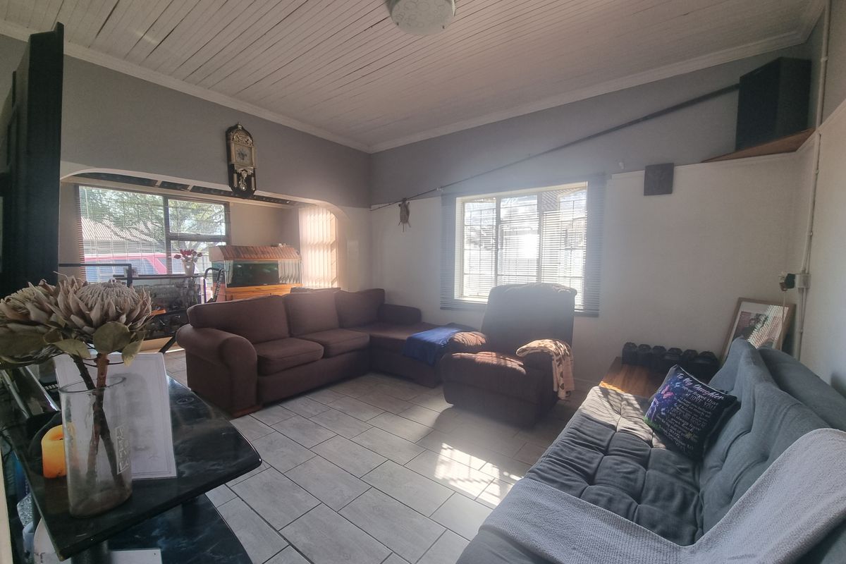 A living room featuring tiled flooring, a timber tongue and groove ceiling, and an archway leading to an adjacent space.