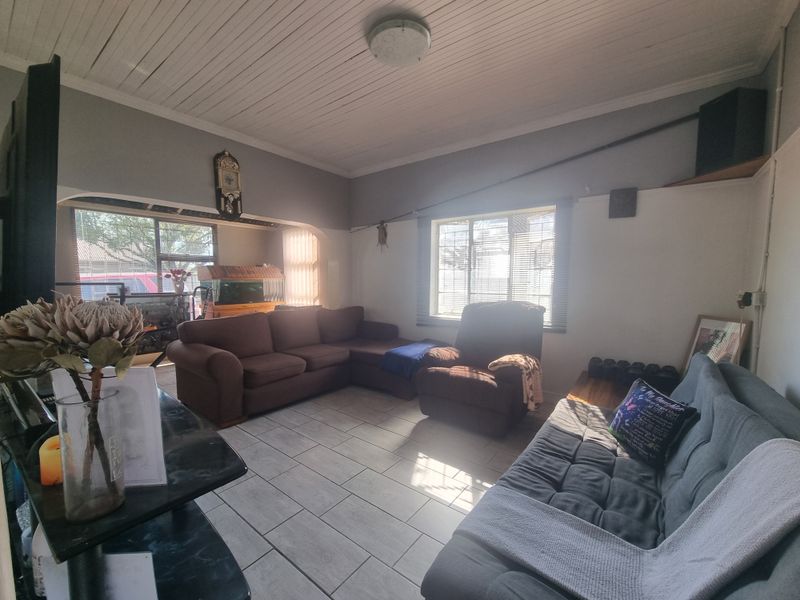 A living room featuring tiled flooring, a timber tongue and groove ceiling, and an archway leading to an adjacent space.