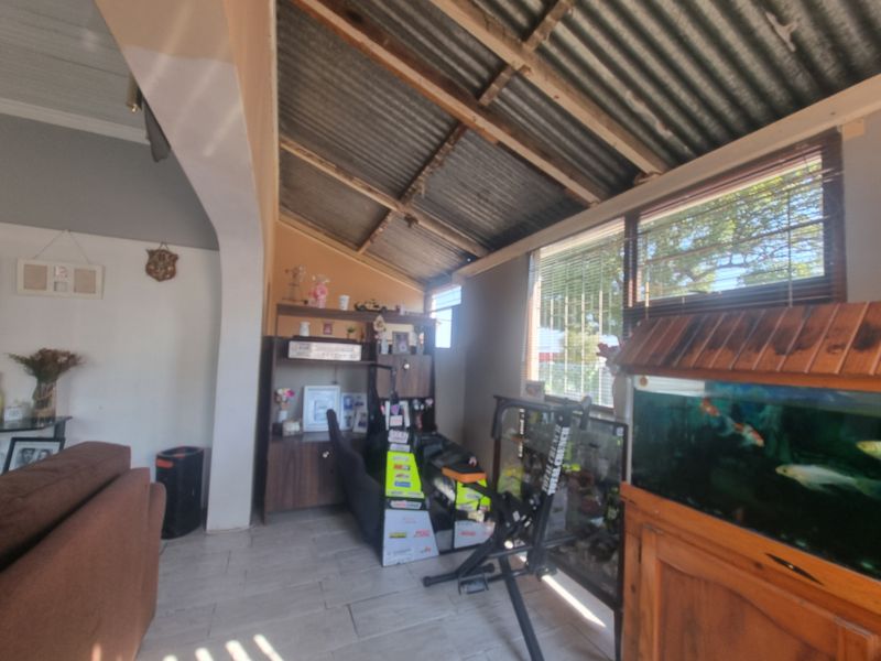 Living area featuring tiled flooring, an arched entryway, and an exposed corrugated metal roof structure.