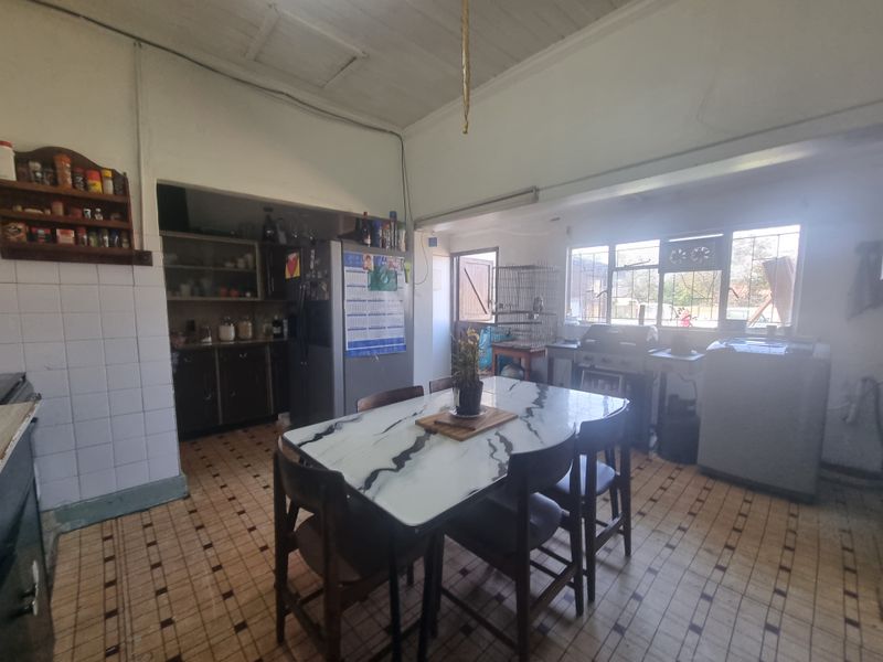 Open plan kitchen and dining area featuring tiled flooring, built-in cabinetry, and a timber ceiling, offering potential for modernization and renovation.