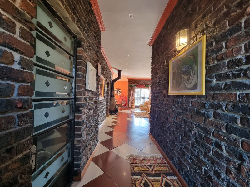 A spacious hallway featuring distinctive exposed brick walls, polished ceramic tile flooring, and a modern freestanding fireplace leading into the living area.