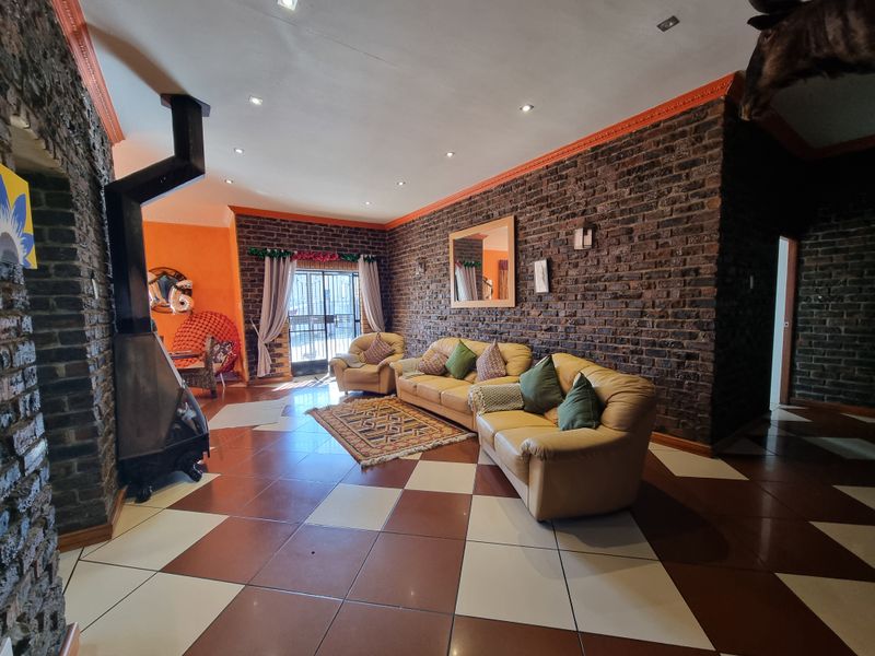 Spacious living room featuring exposed brick walls, a freestanding fireplace, and a distinctive checkered tile floor with access to an outdoor area.