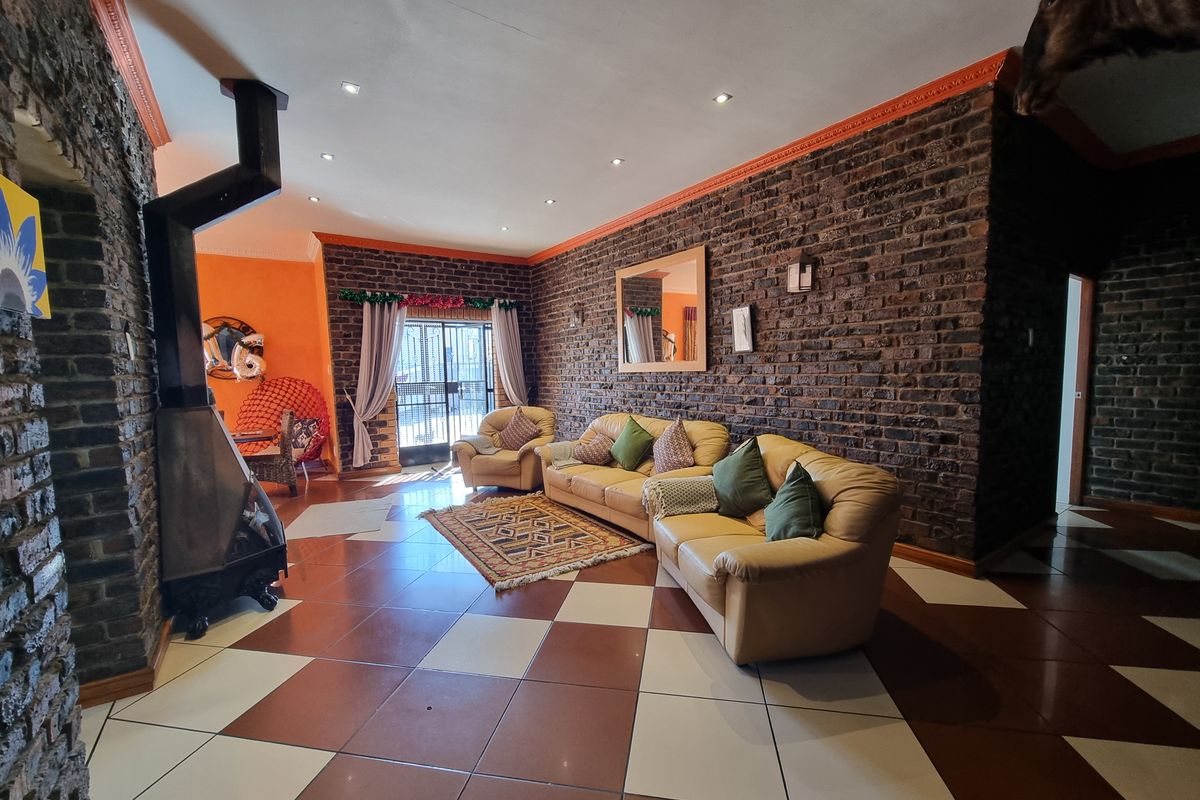 Spacious living room featuring exposed brick walls, a freestanding fireplace, and a distinctive checkered tile floor with access to an outdoor area.