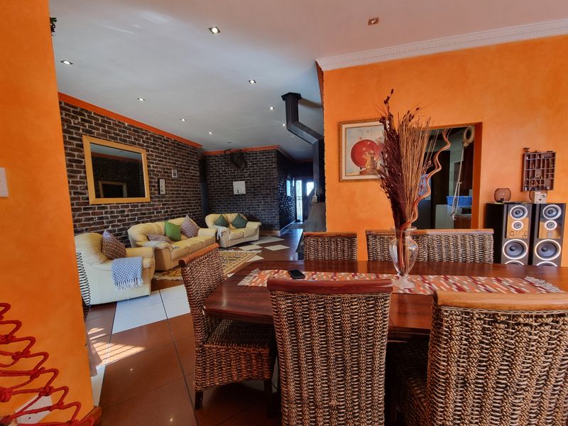 Spacious open-plan living and dining area featuring exposed brick feature walls, tiled flooring, and recessed lighting, creating a warm and inviting atmosphere.
