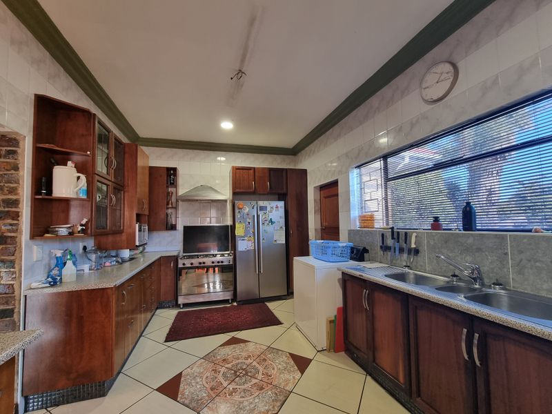 A functional kitchen featuring wooden cabinetry, laminate countertops, a gas stove with extractor, and tiled flooring with a decorative inlay.