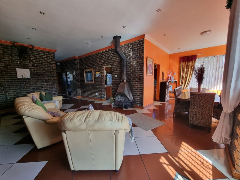 Spacious open-plan living and dining area featuring exposed brick walls, a central freestanding fireplace, and tiled flooring throughout.
