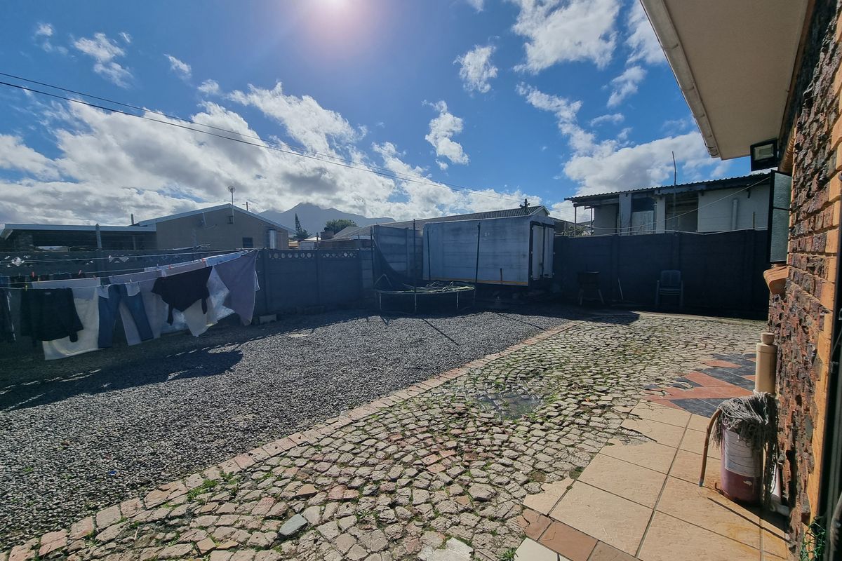 Rear exterior area featuring a combination of cobblestone and tiled paving, enclosed by precast concrete boundary walls.