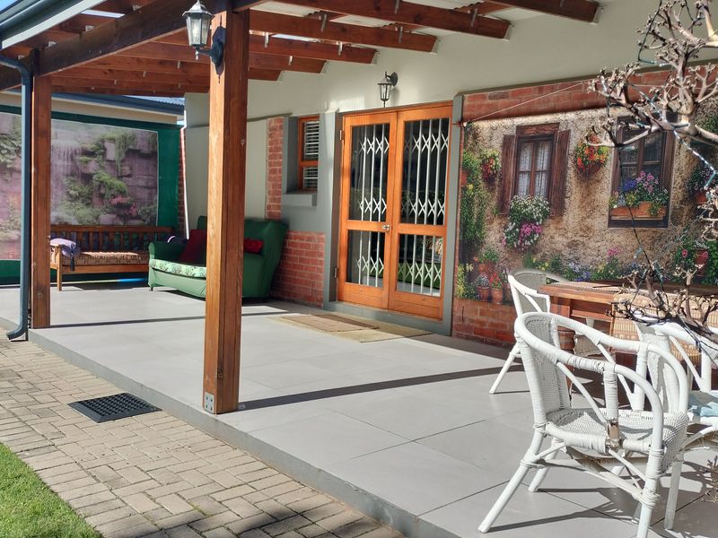 A covered patio area featuring a timber pergola, tiled flooring, and direct access to the home through a secure entrance door.