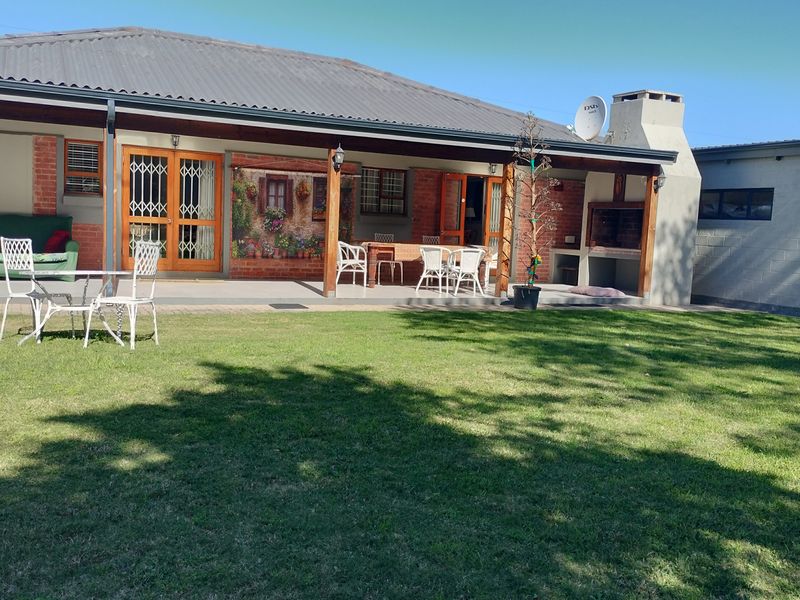 Spacious covered rear patio featuring a built-in braai, brick accents, and direct access to the garden area.