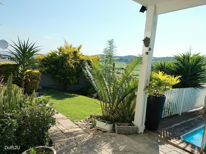 Outdoor pool area featuring a swimming pool, timber decking, and a paved patio space with views of the surrounding landscape.