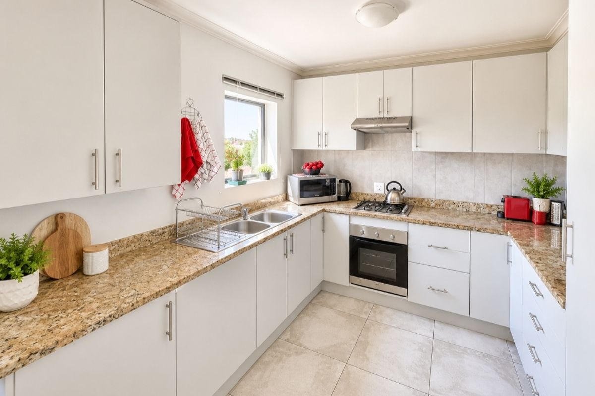 A well-maintained kitchen featuring granite countertops, built-in cabinetry, stainless steel appliances, and tiled flooring with a functional layout.