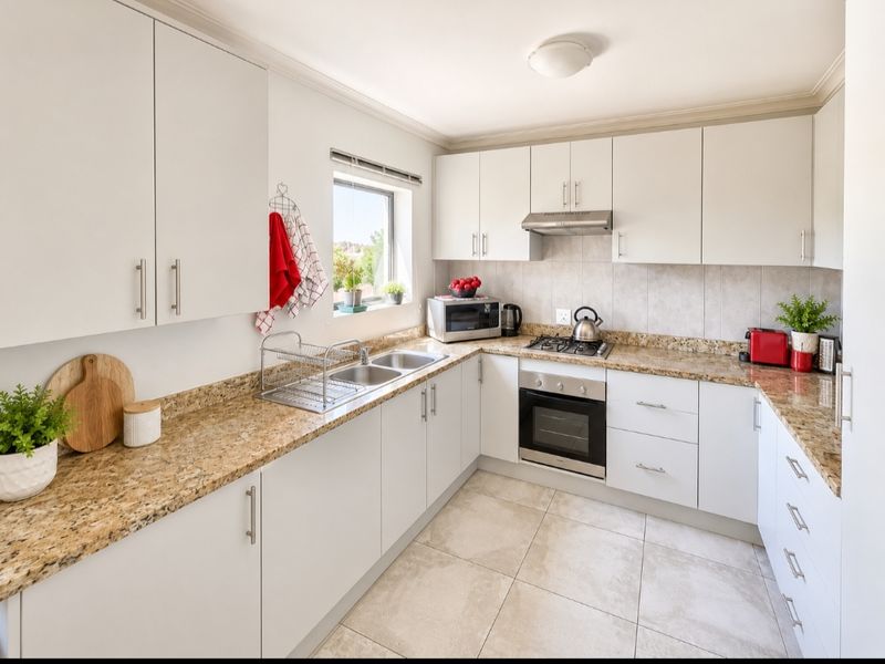 A well-maintained kitchen featuring granite countertops, built-in cabinetry, stainless steel appliances, and tiled flooring with a functional layout.