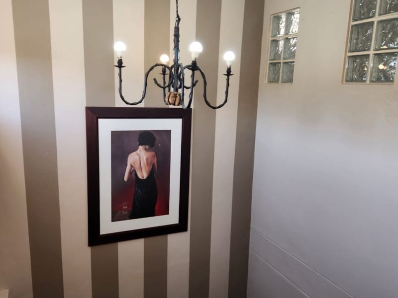 A staircase landing area featuring a decorative wrought iron chandelier, striped accent wall, and glass block windows providing natural light.