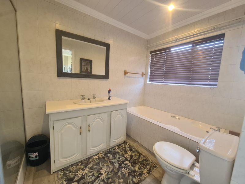 A functional bathroom featuring a vanity cabinet, integrated sink, bathtub, toilet, and a separate shower enclosure with tiled wall finishes.