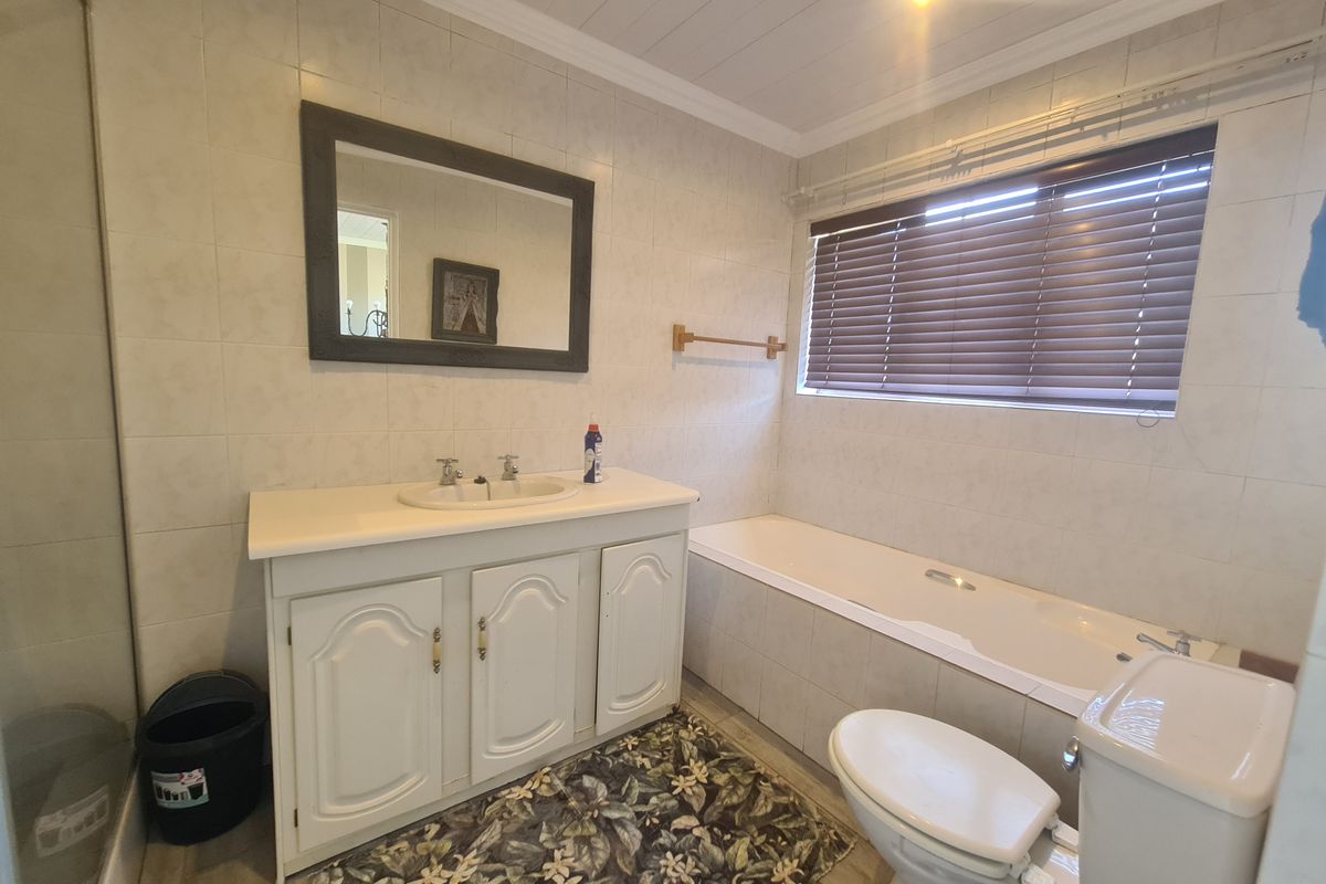 A functional bathroom featuring a vanity cabinet, integrated sink, bathtub, toilet, and a separate shower enclosure with tiled wall finishes.