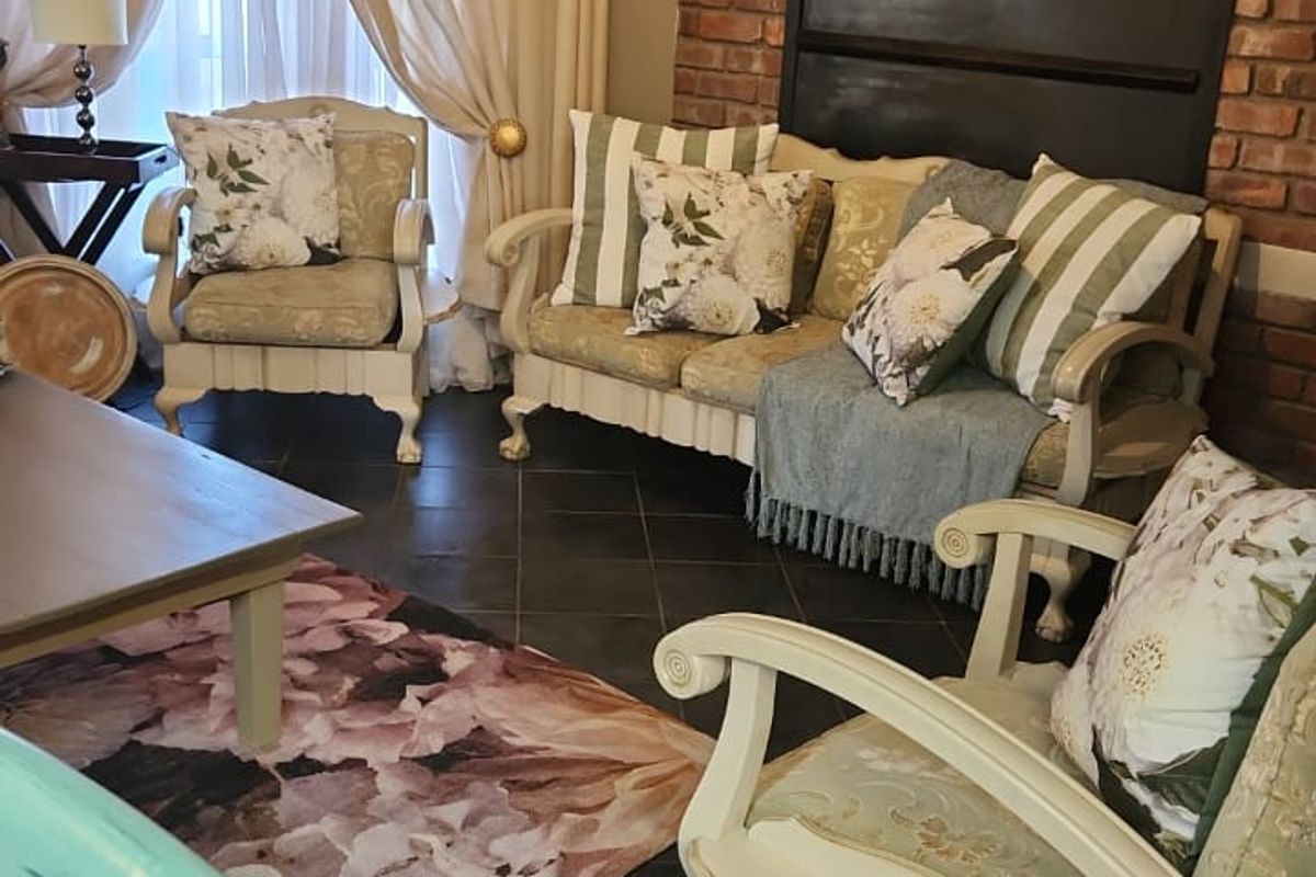 A cozy living room featuring a prominent exposed brick wall and dark tiled flooring, creating a warm and rustic atmosphere.