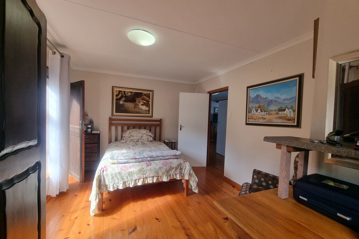 A well-lit bedroom featuring polished hardwood flooring and neutral wall finishes, providing a comfortable and functional living space.
