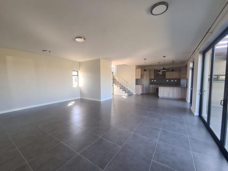 Spacious open-plan living and kitchen area featuring modern tiled flooring, sleek cabinetry, and large sliding doors leading to the outdoor space.