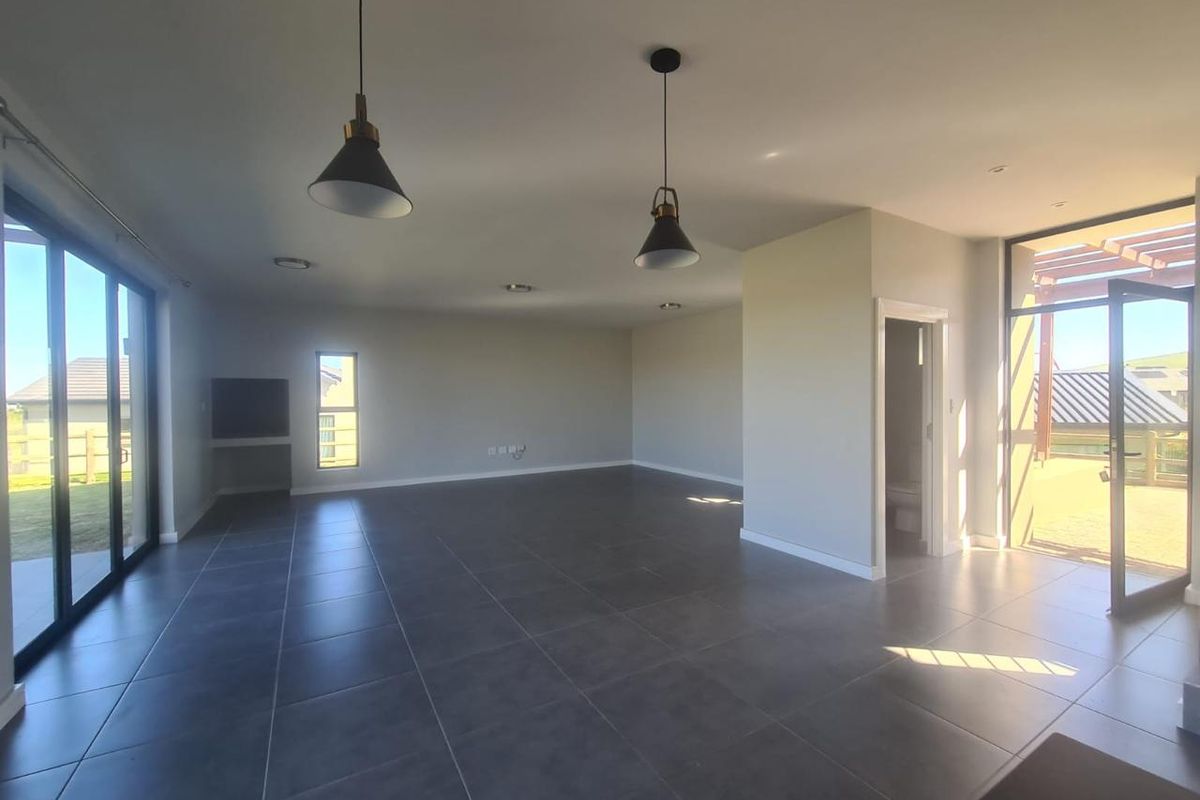 Spacious, modern open-plan living area featuring large format floor tiles, abundant natural light, and direct access to outdoor patio spaces.
