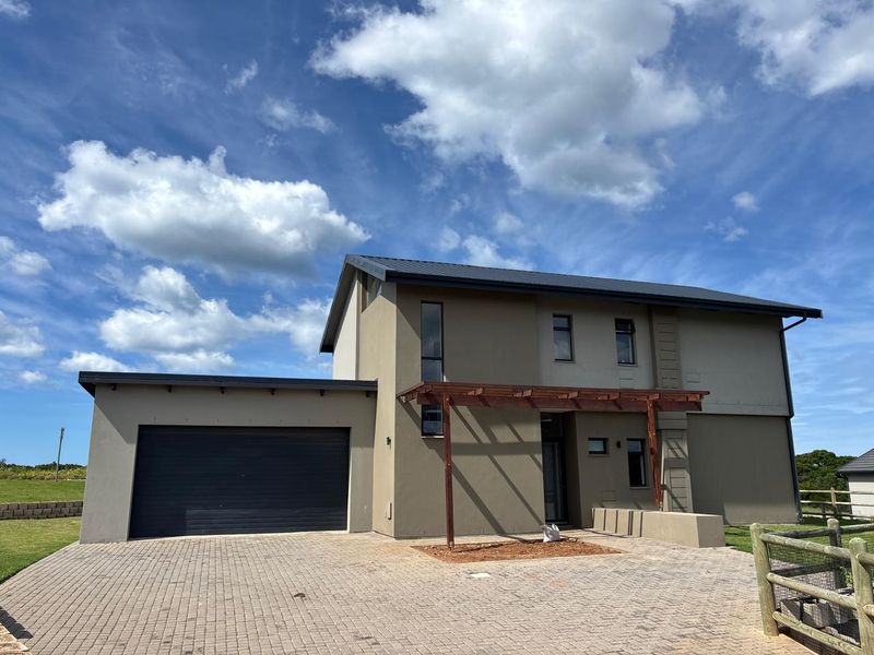 Modern double-story residential home featuring a paved driveway, integrated double garage, and a timber pergola entrance.
