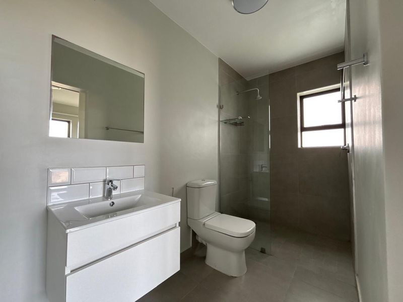 Modern bathroom featuring a sleek vanity, subway tile splashback, and a spacious walk-in shower with a glass screen.
