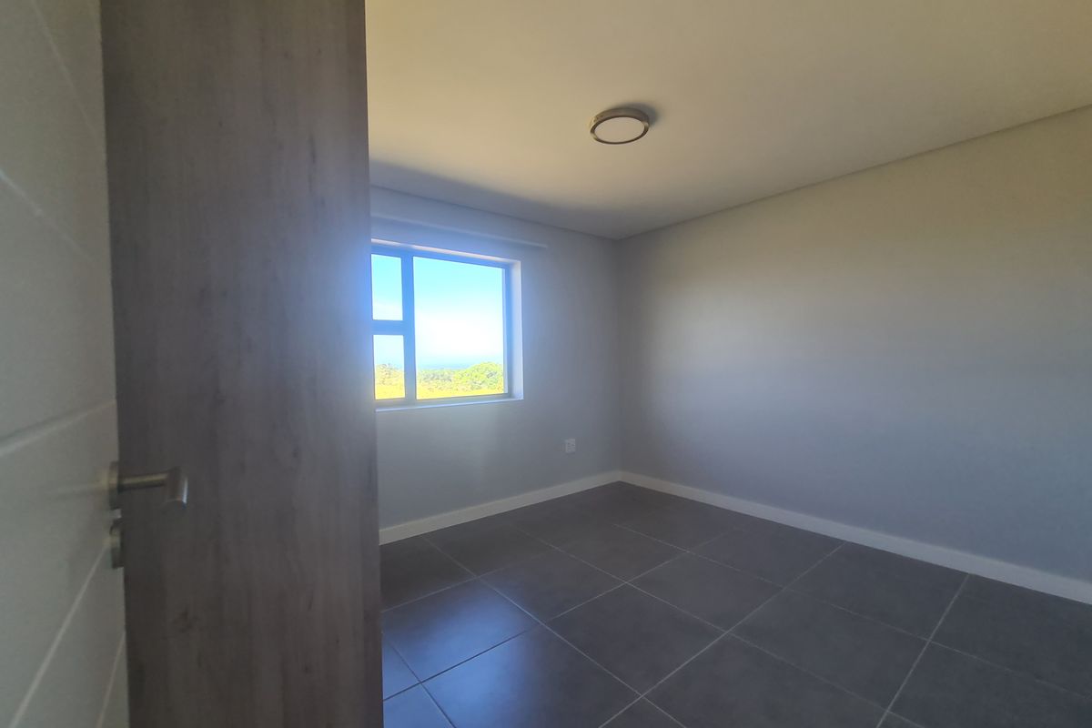A clean, empty bedroom featuring neutral grey tiled flooring, smooth walls, and a modern flush mount ceiling light.