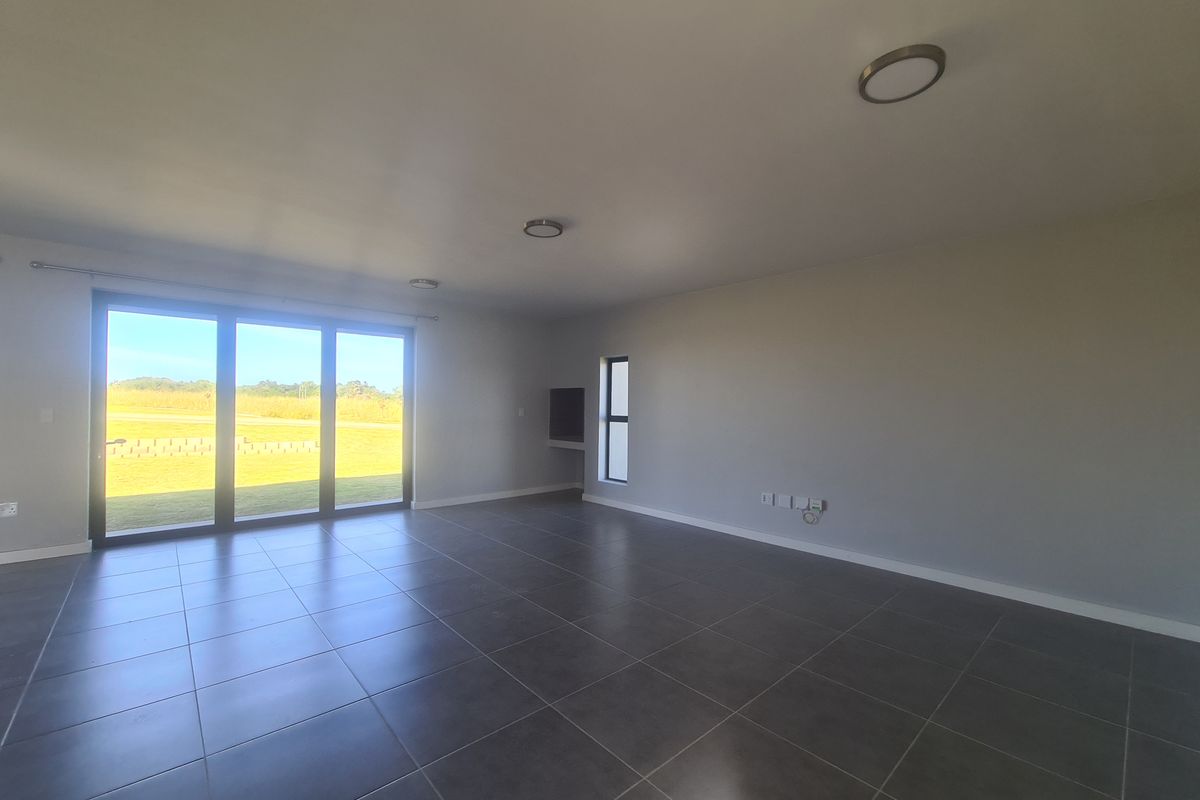 Spacious, modern living area featuring large sliding glass doors, neutral tiled flooring, and a built-in media niche with recessed lighting.