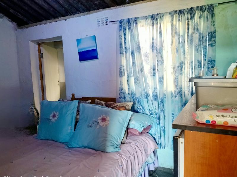A bedroom featuring an exposed corrugated roof structure and basic wall finishes, requiring significant renovation to improve the living space.