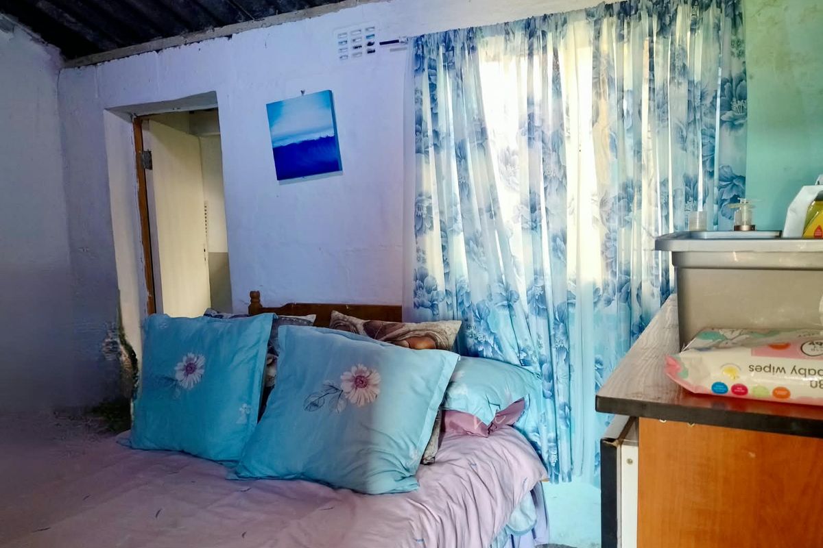 A bedroom featuring an exposed corrugated roof structure and basic wall finishes, requiring significant renovation to improve the living space.