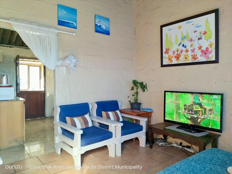 A living room area featuring tiled flooring and exposed masonry walls, providing a rustic foundation for potential interior updates and modernization.