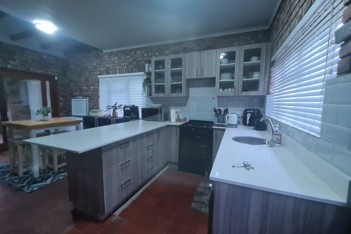 A functional kitchen featuring exposed brick walls, modern quartz countertops, subway tile backsplash, and ample built-in cabinetry with a gas stove.