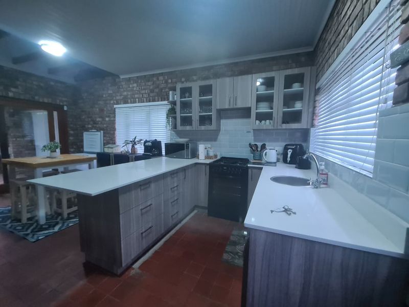 A functional kitchen featuring exposed brick walls, modern quartz countertops, subway tile backsplash, and ample built-in cabinetry with a gas stove.