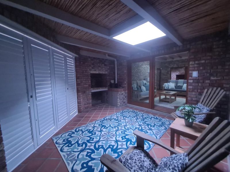 Covered patio featuring exposed brick walls, a built-in braai, skylight, and terracotta flooring, providing a seamless transition to the interior living space.
