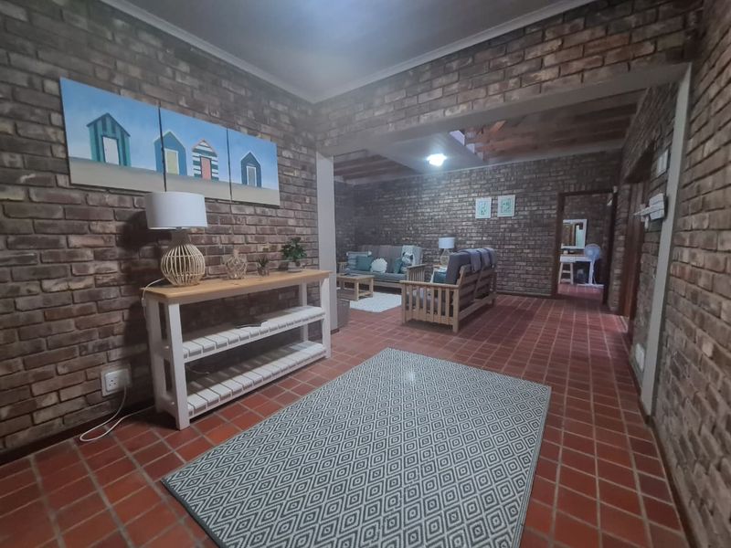 Spacious living area featuring rustic exposed brick walls, traditional terracotta tile flooring, and exposed timber ceiling beams.