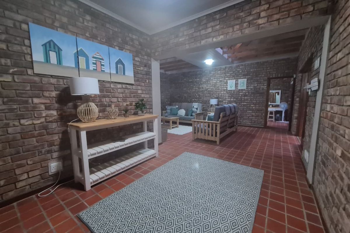 Spacious living area featuring rustic exposed brick walls, traditional terracotta tile flooring, and exposed timber ceiling beams.