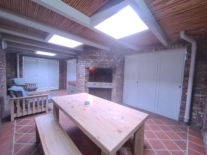 Covered patio area featuring a built-in brick braai, tiled flooring, and skylights, providing a functional outdoor entertainment space.