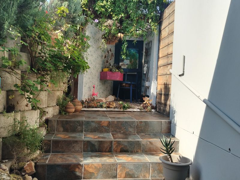 A rear outdoor area featuring a tiled staircase with a handrail, flanked by a retaining wall and timber-clad wall section.