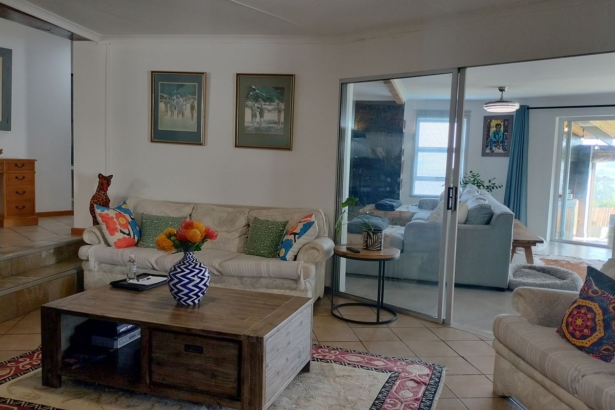A living room featuring tiled flooring, a raised floor section, and a sliding glass door leading to an adjacent living space.