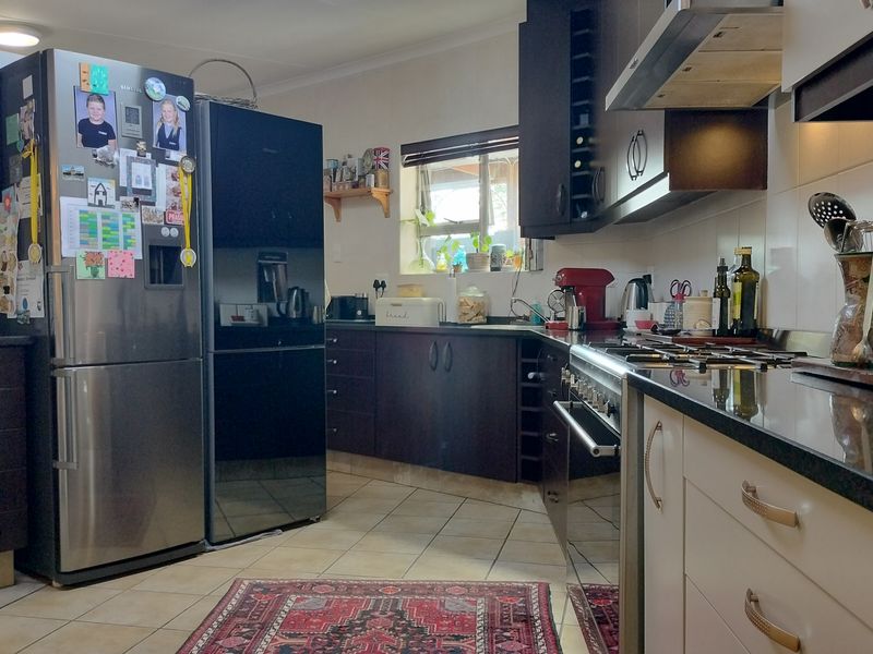 A functional kitchen featuring dark wood cabinetry, granite countertops, a gas stove with extractor fan, and tiled flooring.