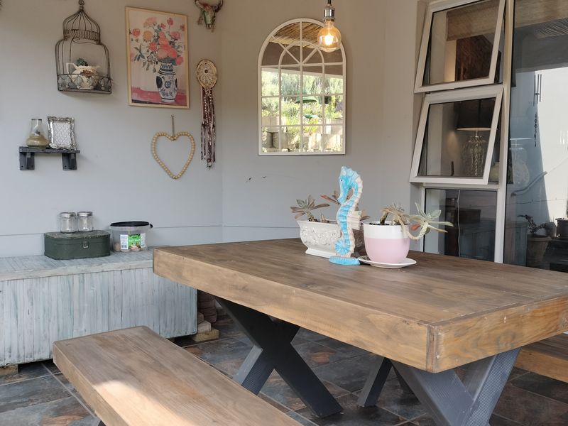 A covered patio area featuring slate tile flooring, top-hung windows, and a sliding glass door, providing a functional outdoor entertainment space.