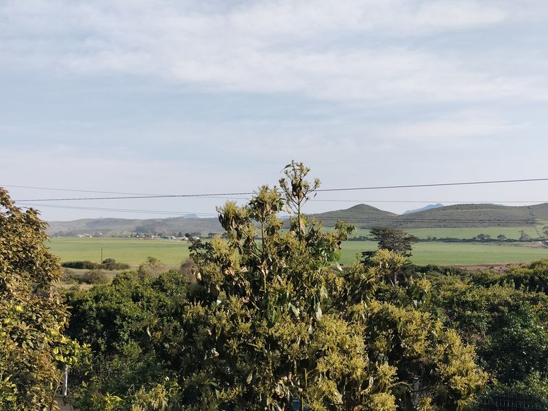A scenic elevated view overlooking lush green fields and rolling hills in the distance.