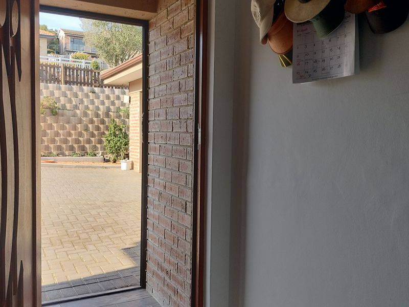 An interior entryway looking out onto a paved rear patio area with a brick retaining wall.