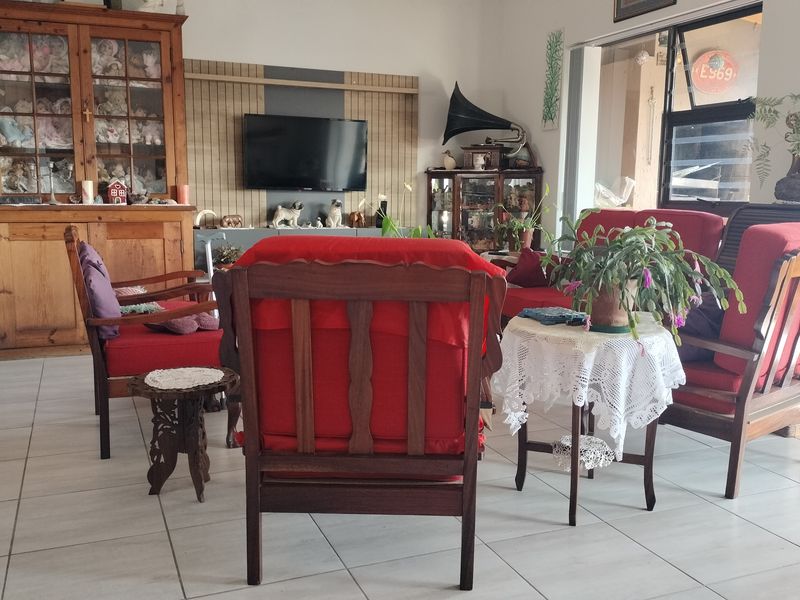 A living room featuring tiled flooring and timber wall paneling, with access to an outdoor area through a sliding glass door.