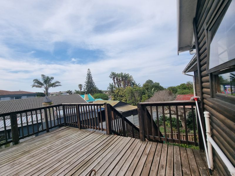 An elevated timber balcony featuring wooden decking and balustrades, offering an open outdoor space with views of the surrounding neighbourhood.