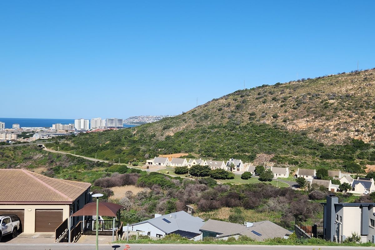 A scenic elevated view overlooking a coastal landscape, hillside terrain, and surrounding residential development.