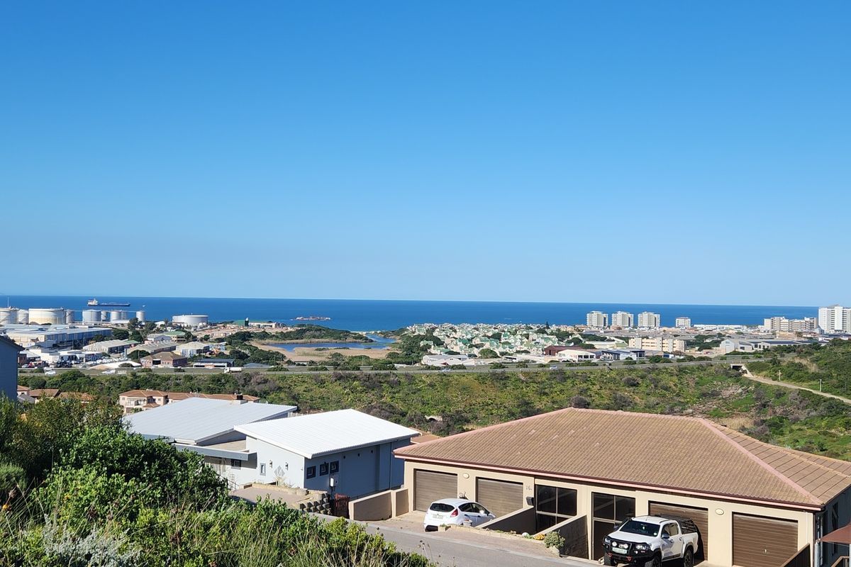 An elevated panoramic view overlooking the coastal landscape, residential area, and the ocean horizon.