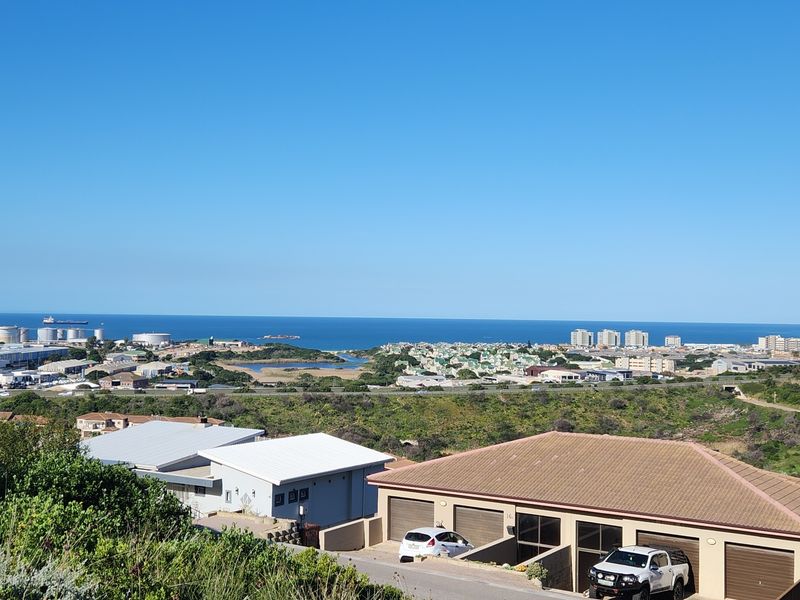 An elevated panoramic view overlooking the coastal landscape, residential area, and the ocean horizon.